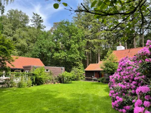 un jardín con flores rosas y una casa en Landgoed Dennenholt - 5 unique holiday homes en Vierhouten