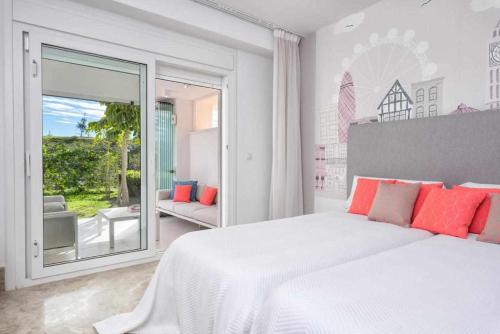 1 dormitorio blanco con 1 cama blanca grande con almohadas de color naranja en Marbella Golf y Beach Santa Clara By Houselogy en Marbella