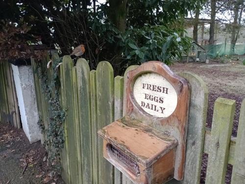 una silla de madera con un cartel en una valla en Lough Shore Cottage, en Magherafelt