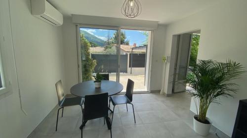 une salle à manger avec une table et des chaises et une grande fenêtre dans l'établissement La perle de provence, appartement neuf en rez de Jardin clos, au calme, clim, salle d'eau dans chaque chambre, à 900m du centre de Nyons, à Nyons