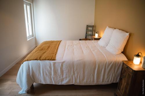 a bedroom with a bed with white sheets and a window at Entre Chênes et Pins - Gîte de groupe 3 étoiles in Hostens
