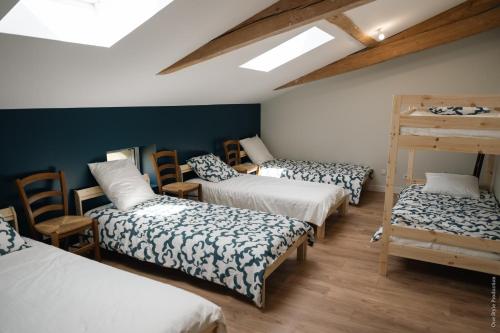 um quarto com 4 camas, cadeiras de madeira e uma clarabóia em Entre Chênes et Pins - Gîte de groupe 3 étoiles em Hostens