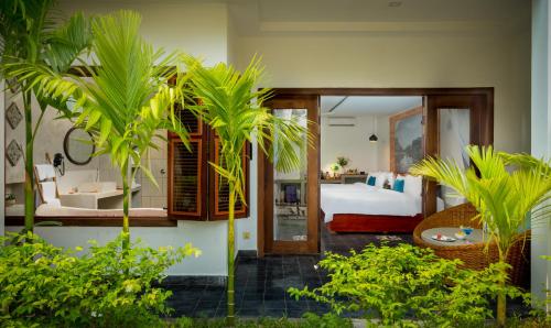 a bedroom with a bed and a room with palm trees at Bopha Wat Bo Residence in Siem Reap