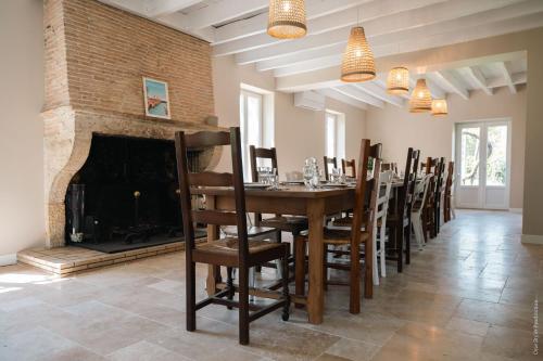 een eetkamer met een open haard en een tafel en stoelen bij Entre Chênes et Pins - Gîte de groupe 3 étoiles in Hostens