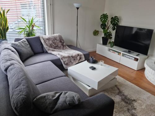 a living room with a couch and a tv at Cosy & modern 3 bedroom house close to the beach in Katwijk aan Zee
