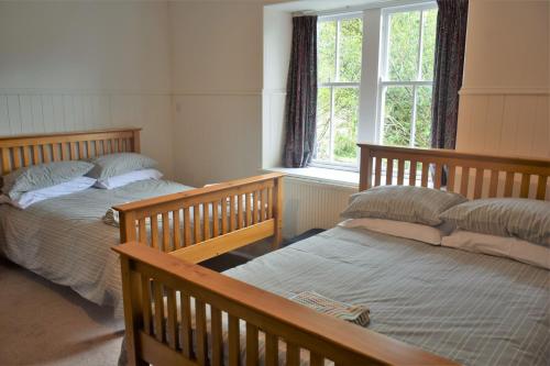 a bedroom with two beds and a window at The Stables in Carsethorn