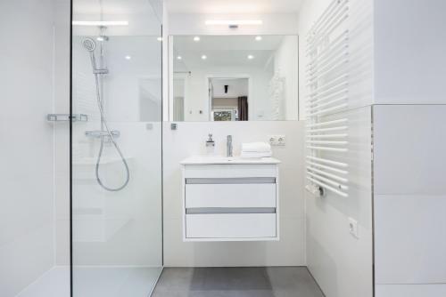 La salle de bains blanche est pourvue d'une douche et d'un lavabo. dans l'établissement Strandresidenzen Binz-Prora Strandresidenzen Binz-Prora D1 3, à Binz
