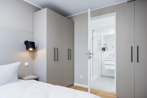 um quarto com uma cama branca e uma cabina de duche ao nível do chão em Strandresidenzen Strandresidenzen Haus Dänholm 2 3 em Binz