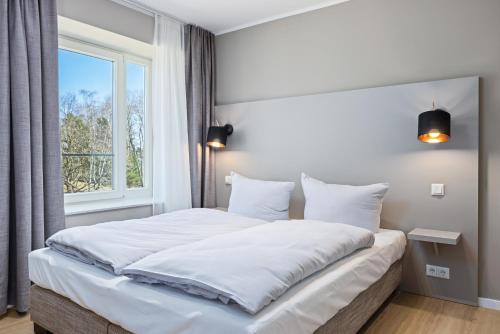 - une chambre avec un grand lit blanc et une fenêtre dans l'établissement Strandresidenzen Strandresidenzen Haus Dänholm 2 2, à Binz