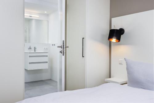 - une chambre avec un lit blanc et une salle de bains dans l'établissement Strandresidenzen Strandresidenzen Haus Dänholm 2 2, à Binz