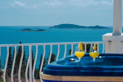 a table with two glasses on a balcony with the water at Aurora Seaview Apartment in Mlini