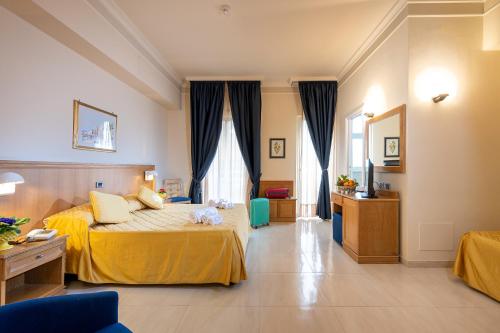 una camera d'albergo con letto con lenzuola gialle di Hotel Sabbie d'Oro a Giardini Naxos