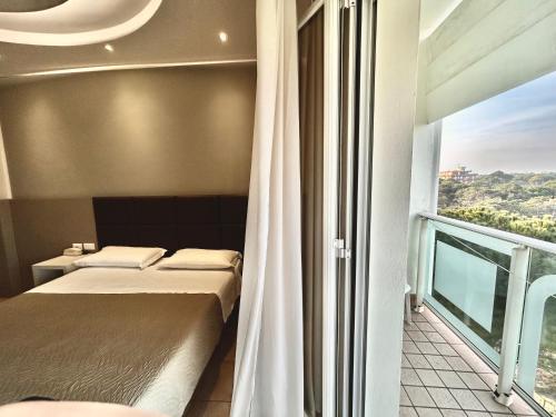 a bedroom with two beds and a large window at Hotel Adria in Milano Marittima