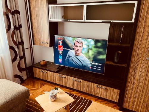 een woonkamer met een flatscreen-tv op een entertainmentcentrum bij Adona Residence in Oradea