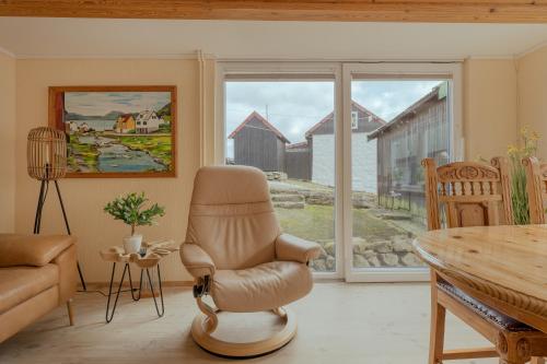 a living room with a chair and a table at Cozy Cottage / 3BR / Hiking / Nature in Við Gjógv