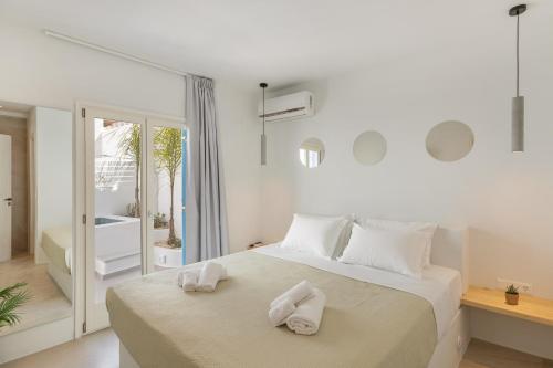 Utopia luxury apartments في ناوسا: غرفة نوم بيضاء مع سرير عليه مناشف