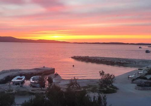 a sunset over a body of water with cars parked at Beach Apartment w Sea Views, 3x Bedrooms w En-Suites in Šibenik