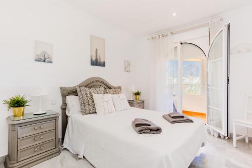 Un dormitorio blanco con una cama grande y una ventana en Modern apartment with terrace, en Marbella
