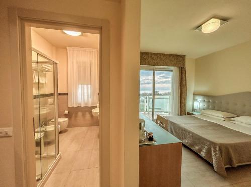 a bedroom with a bed and a view of a bathroom at Hotel Adria in Milano Marittima
