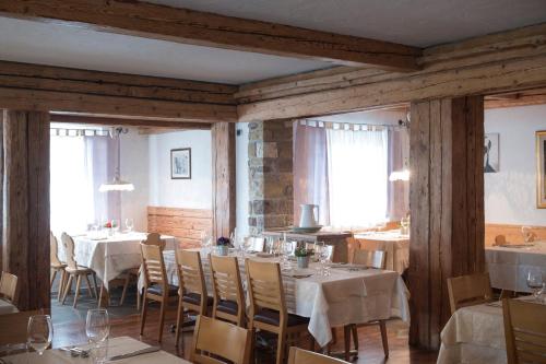 een eetkamer met tafels en stoelen en ramen bij Hotel Los Andes in Castello di Fiemme