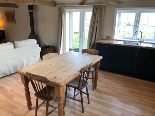 eine Küche mit einem Holztisch und Stühlen im Zimmer in der Unterkunft The Cowshed in Salisbury