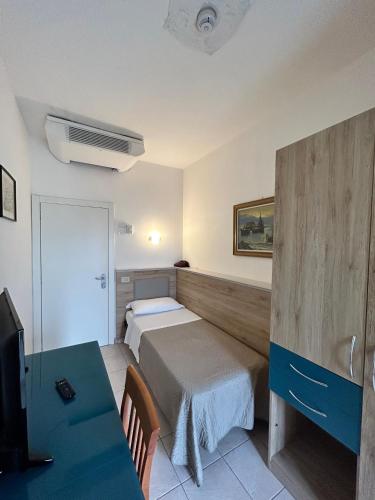 a room with two beds and a table and a tv at Hotel Adria in Milano Marittima