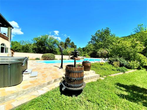 a fountain in the yard of a house with a pool at Gîte et chambre d'hôtes LE MERCOIRE, piscine chauffée et jacuzzi in Aubenas