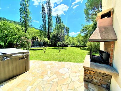 a patio with a grill and a field of grass at Gîte et chambre d'hôtes LE MERCOIRE, piscine chauffée et jacuzzi in Aubenas