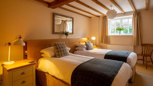 a bedroom with two beds and a window at Old Mill Barn in Chipping Campden
