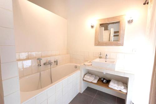 ein Badezimmer mit einer Badewanne, einem Waschbecken und einem Spiegel in der Unterkunft Appartement d'une chambre avec jardin amenage et wifi a Cons la Grandville in Cons-la-Grandville