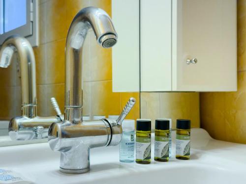 a sink with three bottles of toothbrushes and a faucet at Kairi Cozy 92sqm apt in Nea Smirni in Athens