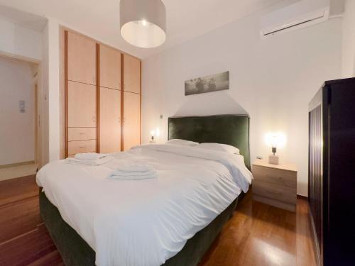 una camera da letto con un grande letto bianco con testiera verde di Kairi Cozy 92sqm apt in Nea Smirni ad Atene