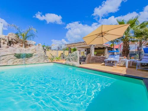 a swimming pool with an umbrella and a table and chairs at Villetta Oasi nelle Rocce con Piscina Privata in Acquarica del Capo