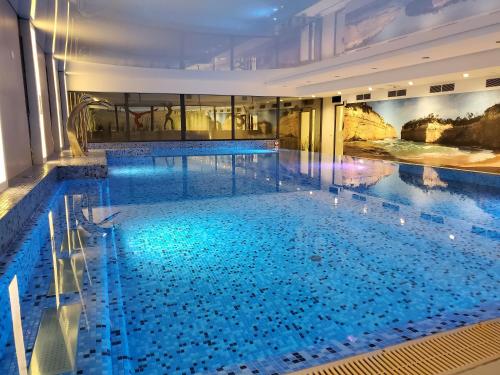 a large swimming pool with blue water in a building at Antonińska Resort SPA in Boszkowo