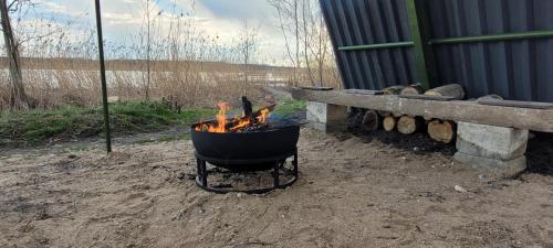 a barbecue grill with fire in it next to a bench at Vigio Brasta camping in Elektrėnai