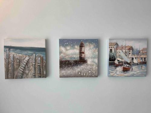 three paintings of a lighthouse on a wall at Fregene's Studio Monolocale in Fregene