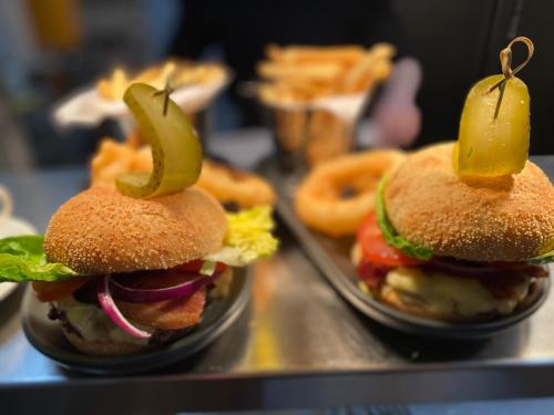 two hamburgers with pickles on top of them and onion rings at The Egerton Arms Astbury in Congleton