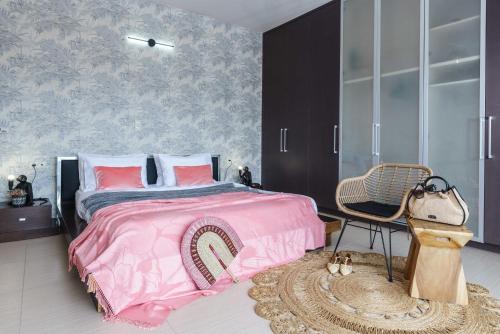 a bedroom with a pink bed and a chair at Villa Capparis in Moírai