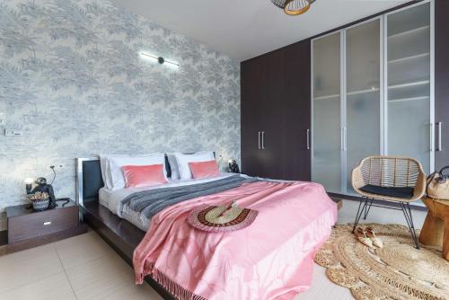 a bedroom with a bed with pink sheets and a chair at Villa Capparis in Moírai