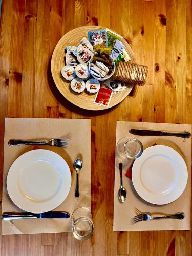 a table with white plates and silverware on a wooden table at Il Casale di David in Pontedera