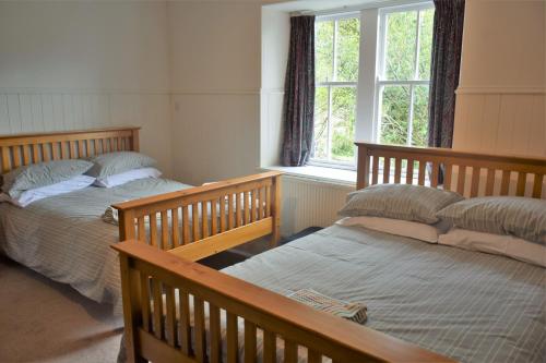 a bedroom with two beds and a window at Coachmans Cottage in Carsethorn