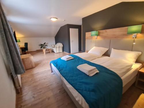een slaapkamer met een groot bed en een blauwe deken bij Gasthaus Frörup in Oeversee
