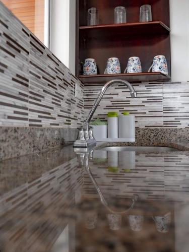 a bathroom sink with a faucet and cups on a shelf at Chalet Familiar Delpilar, Full equipado, zona de Jacuzzi! in Sogamoso