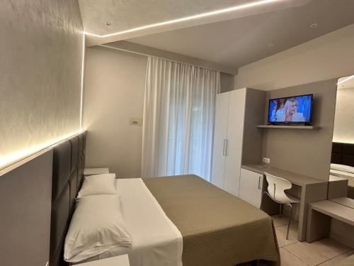a hotel room with a bed and a desk and a television at Hotel Adria in Milano Marittima