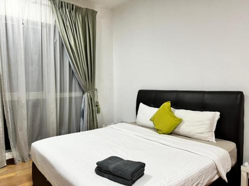 ein Bett mit einem schwarzen Kopfteil und zwei gelben Kissen in der Unterkunft Regalia Suites KL Infinity Pool _ by MygeHomes in Kuala Lumpur