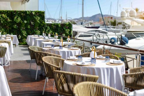a row of tables and chairs on a deck with boats at Hotel Port Salins by Pierre & Vacances in Empuriabrava