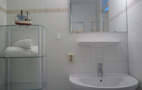 ein weißes Badezimmer mit einem Waschbecken und einem Spiegel in der Unterkunft Terminated in Cadzand