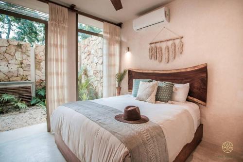 een slaapkamer met een bed met een hoed erop bij Jungle hideaway 2BR/plunge pool in Tulum