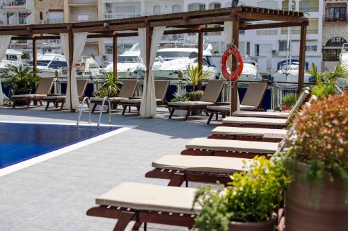a row of lounge chairs and a swimming pool at Hotel Port Salins by Pierre & Vacances in Empuriabrava