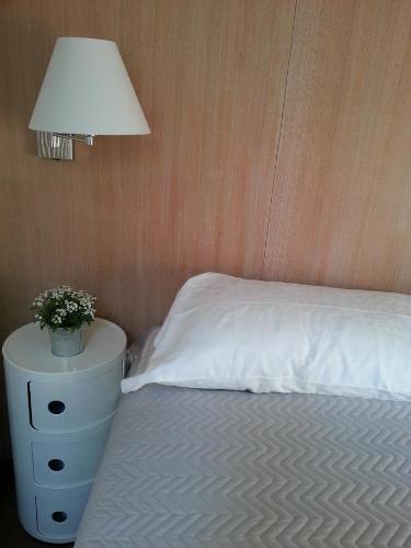 1 dormitorio con cama blanca y mesita de noche con lámpara en B&B Bergamo Alta, en Bérgamo